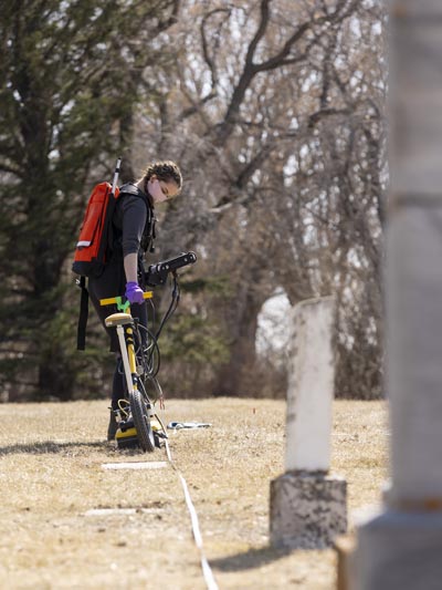 An archaeology student pulls a ground-penetrating radar machine at Nutana Pioneer Cemetery in Saskatoon in April 2021 as part of a learning exercise led by Dr. Terence Clark. (Photography: David Stobbe)