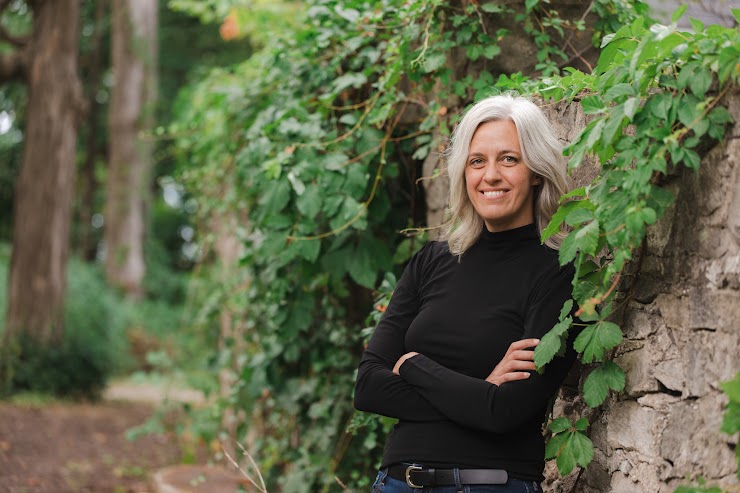 Woman with gray hair leaning against a stone wall