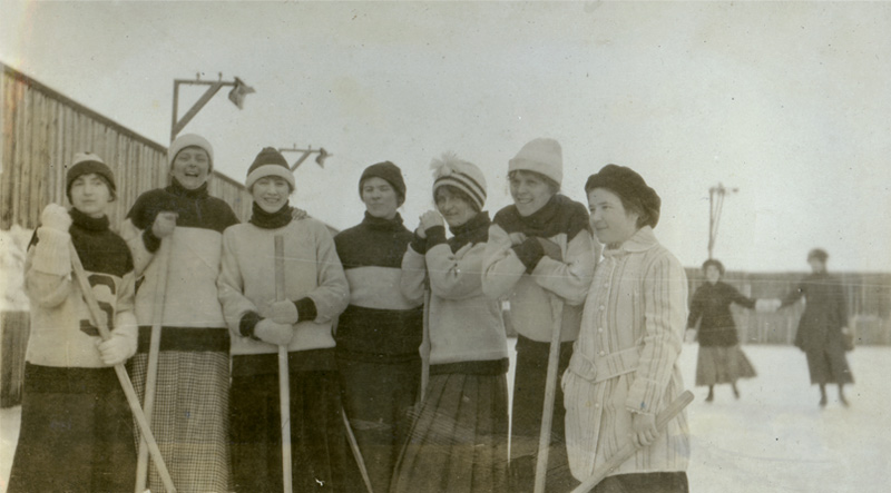 Nan McKay played on the women’s hockey team during her time at USask. In the background, two women are pictured holding hands.
