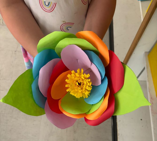 child holding large paper flower