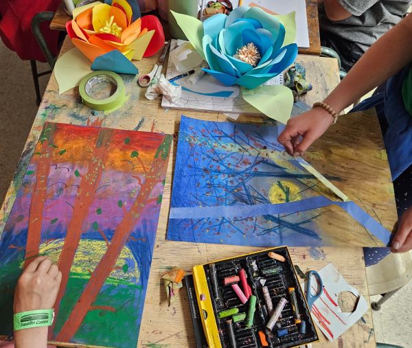 children's hands making pastel drawings